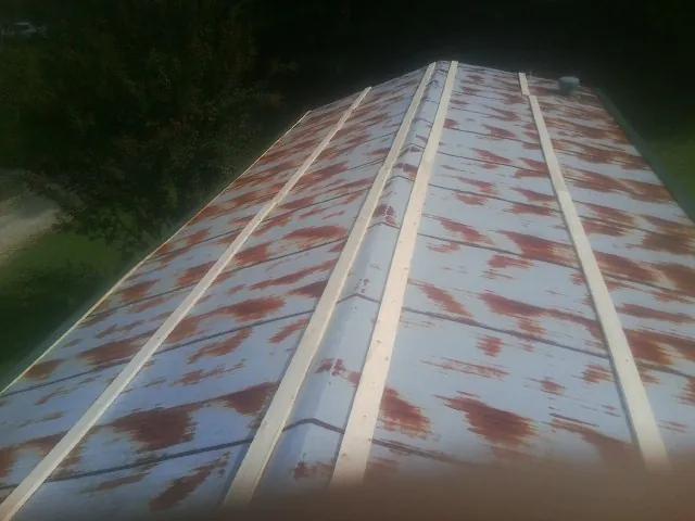 Rusted metal roof panels with new wood purlins before replacement — Storm Damage Roof Repair in Northern Cambria by Roofing Brothers