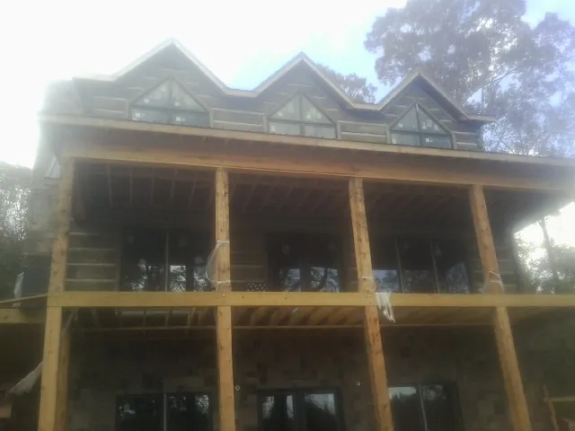 Dormers and porch framing on a large log home under construction — Roof Coating work by our crew in Northern Cambria