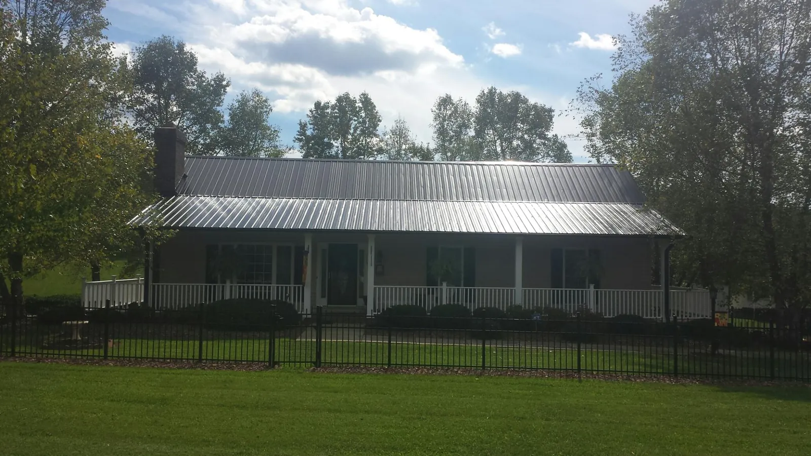 Gray metal roof on a brick ranch with a full width front porch — Gutter Guard Installation work by our crew in Northern Cambria
