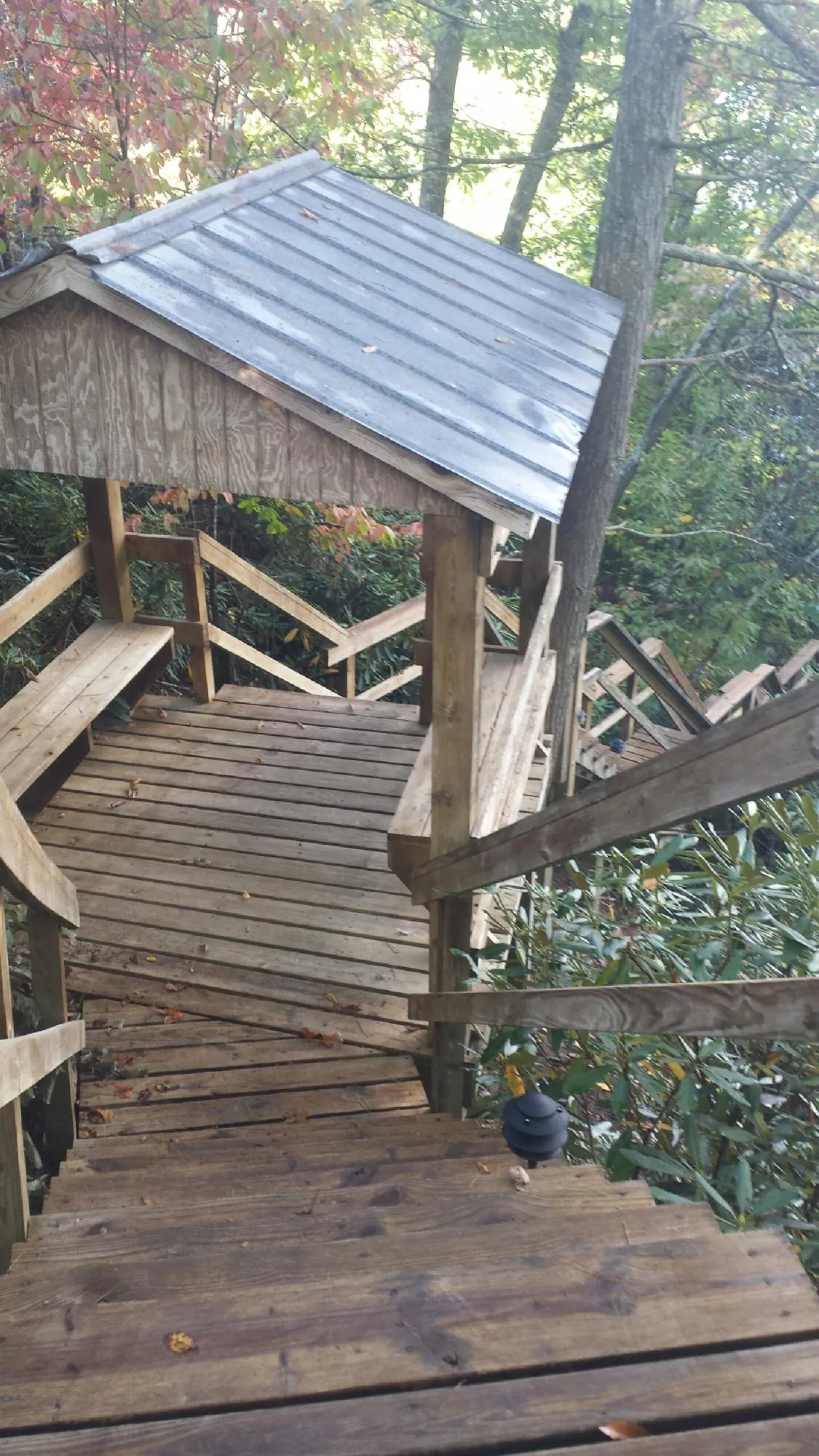 Metal roofed shelter over wooden steps on a wooded walkway — Skylight Repair & Installation work by our crew in Northern Cambria