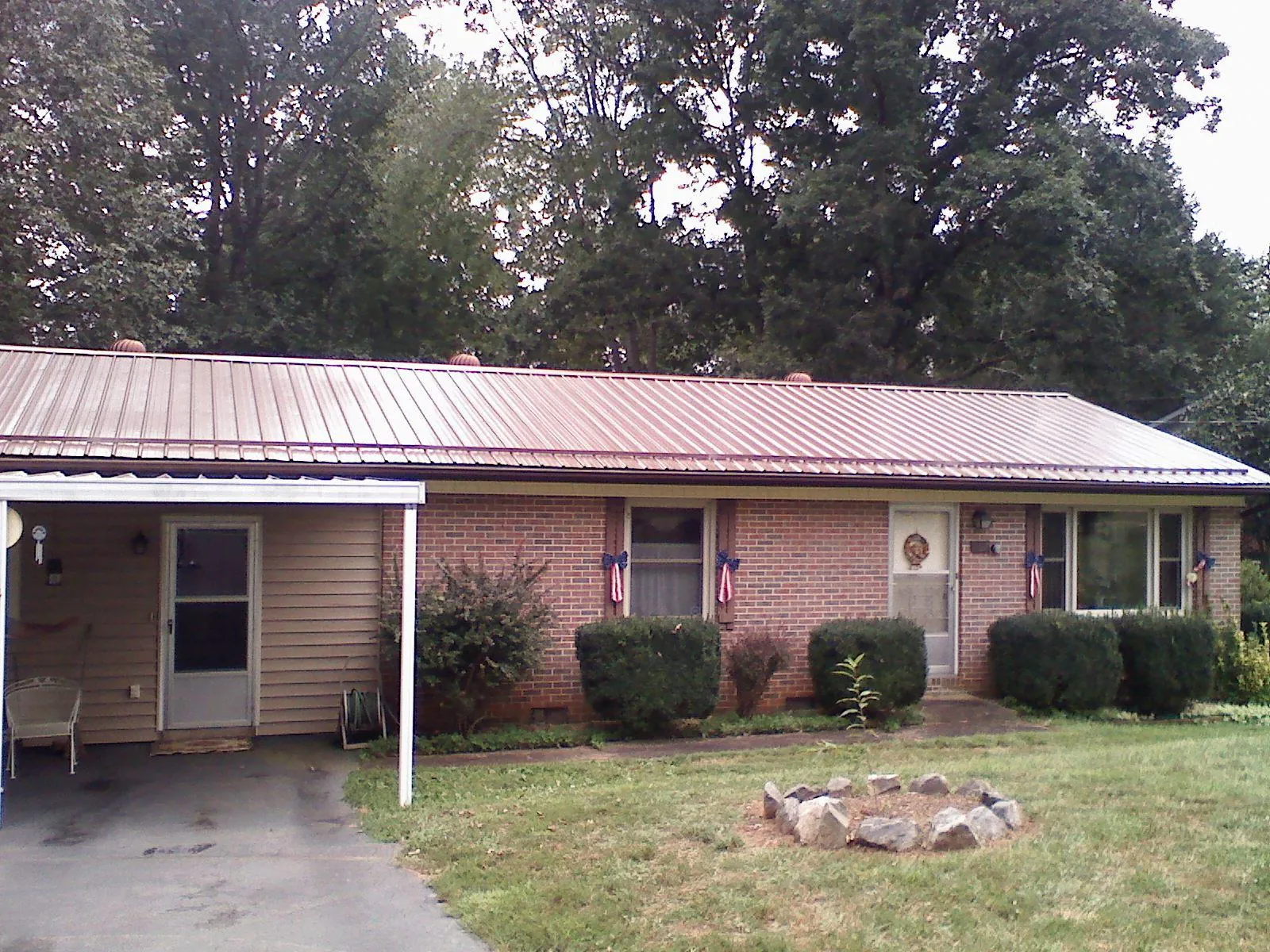 Bronze metal roof and carport on a brick ranch home — Roof Repair work by our crew in Northern Cambria