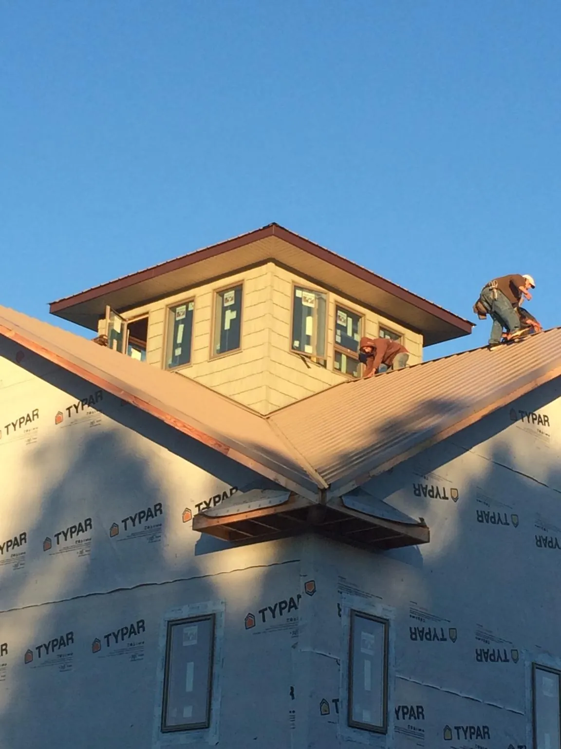 Roofers working around a rooftop cupola on a new metal roof at sunset — Roof Waterproofing in Northern Cambria by Roofing Brothers
